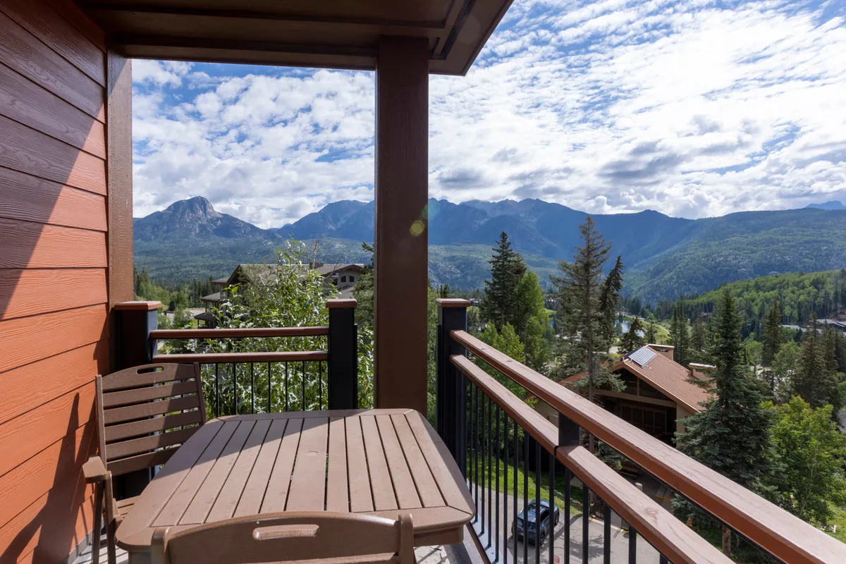 A peaceful outdoor seating area overlooks the majestic San Juan Mountains. The wooden railing and comfortable chairs invite guests to relax, enjoy a book, or savor a morning coffee while taking in panoramic mountain views.